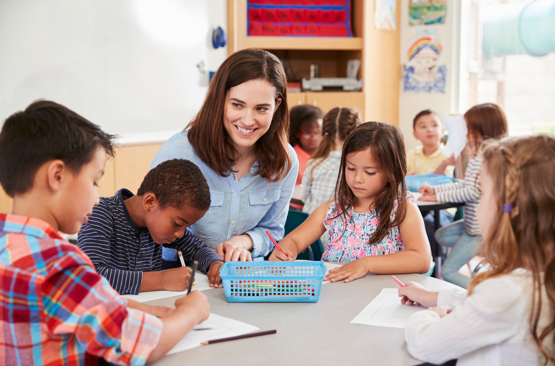 Teacher sitting at table with young students